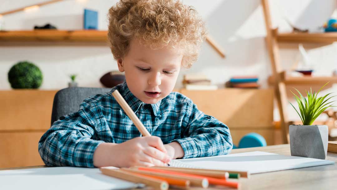 young child drawing at desk